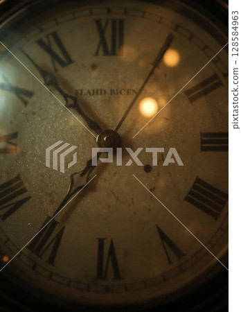 Extreme close-up of a vintage clock face with Roman numerals. The dusty, weathered surface and warm, moody lighting evoke a sense of nostalgia and the passage of time. Antique and retro concept. 128584963