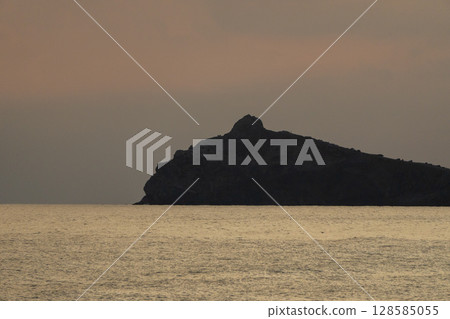 Sunset Seascape Mountain Silhouette Calm: Dramatic evening view with dark mountain against golden sea, creating peaceful scenery. 128585055