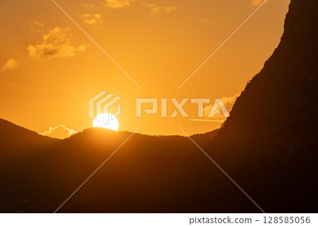 Sunset Mountains Light: Dusk in Saint Lucia, with sun setting behind Pitons for scenic views. 128585056