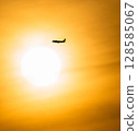 airplane flying against the sun 128585067