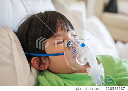 Sick little asian girl inhalation with nebulizer for respiratory treatment 128585687