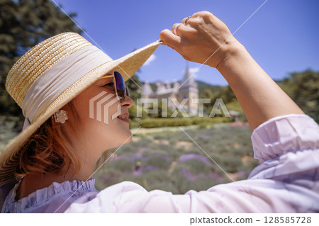 A woman wearing a straw hat and sunglasses is smiling at the camera 128585728