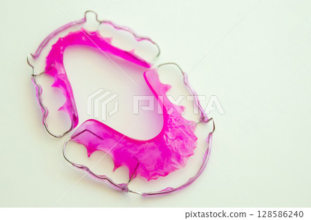 Pink acrylic dental retainer on white background Pink acrylic dental retainer on white background 128586240