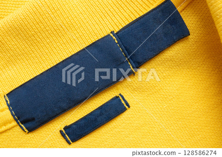 Blank blue laundry care clothes label on yellow shirt fabric texture background Blank blue laundry care clothes label on yellow shirt fabric texture background 128586274