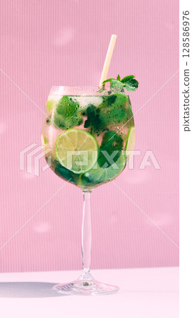 Closeup of Hugo Spritz with lime and mint against pink striped background 128586976