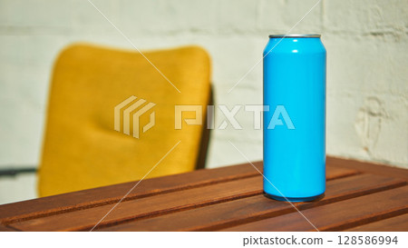 Blue drink can placed on wooden table with a blurred background of a yellow chair for mockup Blue drink can placed on wooden table with a blurred background of a yellow chair for mockup 128586994