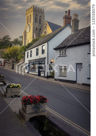 Whitewashed buildings and church in Beer in Devon at dusk 128588079