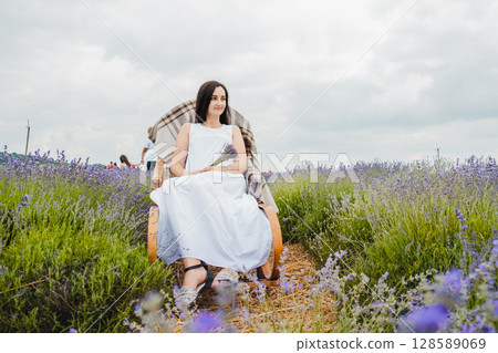In the lavender field, there is a rocking chair where a charming woman sits In the lavender field, there is a rocking chair where a charming woman sits 128589069