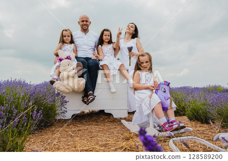 The father and daughters are comfortably seated on an old white chest The father and daughters are comfortably seated on an old white chest 128589200