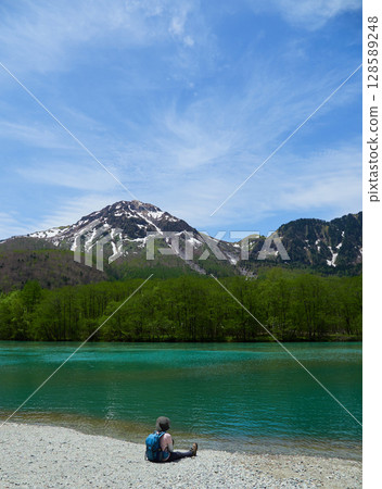 A male tourist taking a rest on the shore of Taisho Pond, a tourist spot in Kamikochi in summer A male tourist taking a rest on the shore of Taisho Pond, a tourist spot in Kamikochi in summer 128589248