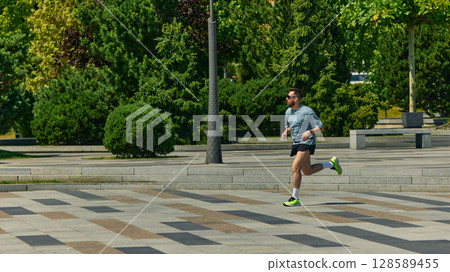 Man jogging in sunny urban park focusing on midlife fitness and health 128589455