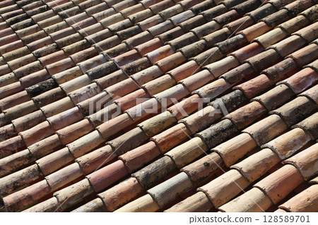 Weathered clay roof tiles showing pattern and texture in sunny outdoor setting during daytime Weathered clay roof tiles showing pattern and texture in sunny outdoor setting during daytime 128589701