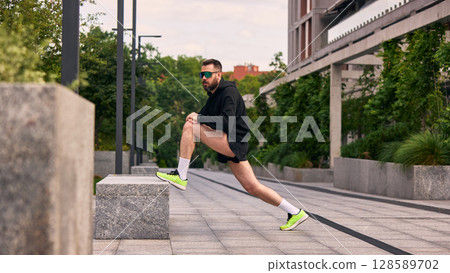 Man extending muscles outside in city park environment endorsing vigorous midlife habits 128589702