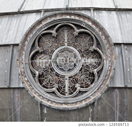 Round stained glass window detail at a historic building in Lourdes 128589713