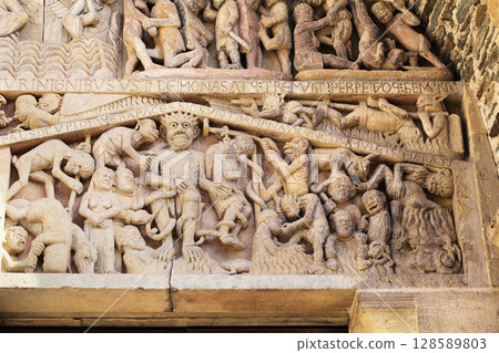 Stone carvings depicting Hell on entrance of Abbey Church of Sainte-Foy in Conques, France Stone carvings depicting Hell on entrance of Abbey Church of Sainte-Foy in Conques, France 128589803