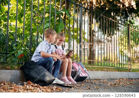 Young school children of boy and girl are together outdoors 128590643