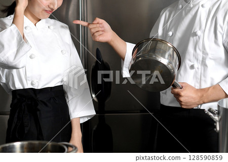 A female chef being scolded by a male chef in the kitchen A female chef being scolded by a male chef in the kitchen 128590859