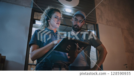 Male Worker and Female Manager Talking, Using Tablet Computer, Standing Outside of Logistics Warehouse 128590935