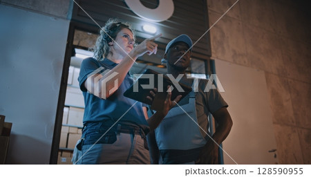 Employee and Female Manager Working in Delivery Service at Night: They Talking, Using Digital Tablet 128590955