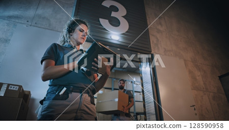 Female Manager Scanning Parcels, Using Digital Tablet. Diverse Employees Carrying Cardboard Boxes 128590958