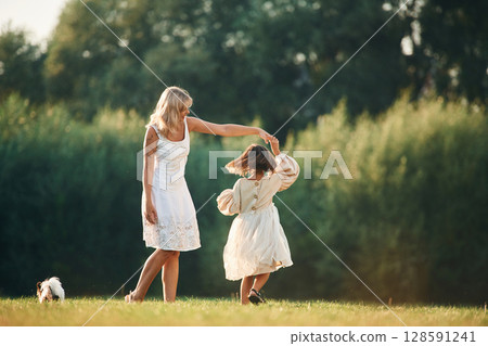 Active, dancing. Woman with her daughter is on the summer field Active, dancing. Woman with her daughter is on the summer field 128591241