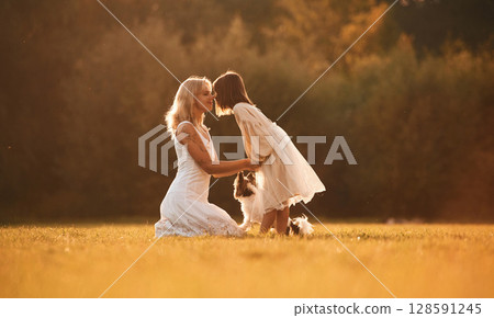 Side view, conception of love and care. Woman with her daughter is on the summer field Side view, conception of love and care. Woman with her daughter is on the summer field 128591245