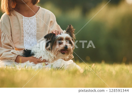 Dog in hands of cute little girl that is on the field 128591344