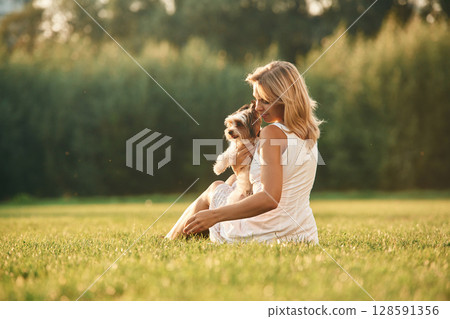 Beautiful woman is with her cute dog outdoors on the field Beautiful woman is with her cute dog outdoors on the field 128591356