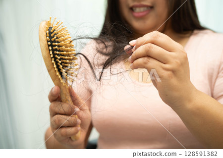 Asian woman have problem with long hair loss attach to comb brush. 128591382