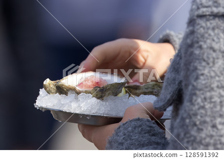 Close-Up of a Fresh Oyster on Ice Held by a Person Close-Up of a Fresh Oyster on Ice Held by a Person 128591392