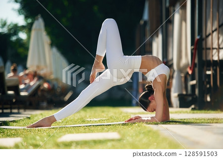 Side view. Young woman in yoga clothes is outdoors 128591503