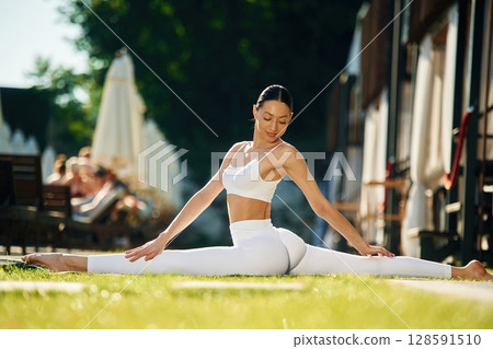 On the green grass. Young woman in yoga clothes is outdoors On the green grass. Young woman in yoga clothes is outdoors 128591510