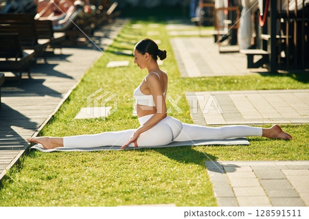 On the green grass. Young woman in yoga clothes is outdoors On the green grass. Young woman in yoga clothes is outdoors 128591511