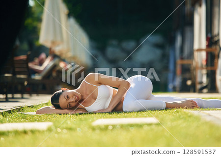Resort exterior behind. Young woman in yoga clothes is outdoors 128591537