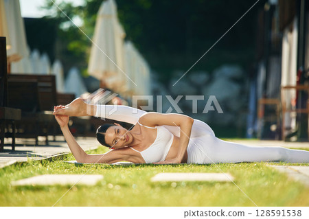 Conception of fitness and flexibility. Young woman in yoga clothes is outdoors Conception of fitness and flexibility. Young woman in yoga clothes is outdoors 128591538