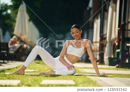 Resort exterior behind. Young woman in yoga clothes is outdoors 128591542