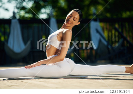 Strength and flexibility. Young woman in yoga clothes is outdoors Strength and flexibility. Young woman in yoga clothes is outdoors 128591564
