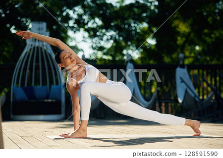 Professional exercises. Young woman in yoga clothes is outdoors 128591590