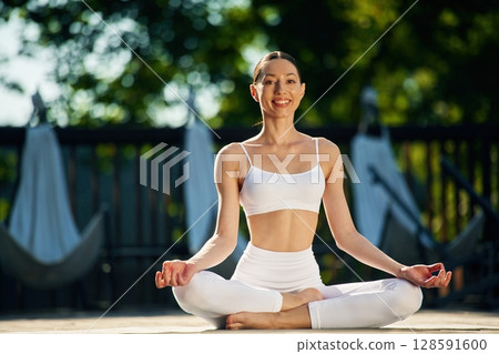 In the lotus pose. Young woman in yoga clothes is outdoors In the lotus pose. Young woman in yoga clothes is outdoors 128591600