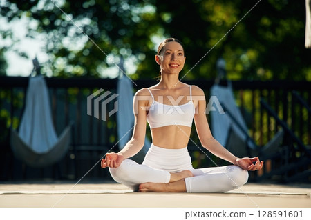 In the lotus pose. Young woman in yoga clothes is outdoors In the lotus pose. Young woman in yoga clothes is outdoors 128591601