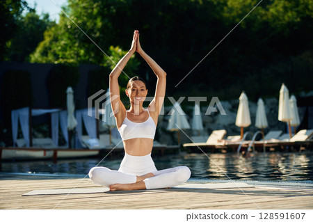 Doing yoga exercises. Woman near pool 128591607