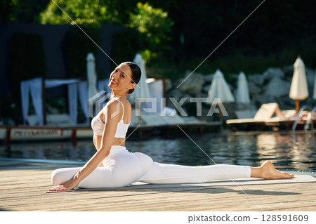 Doing yoga exercises. Woman near pool 128591609