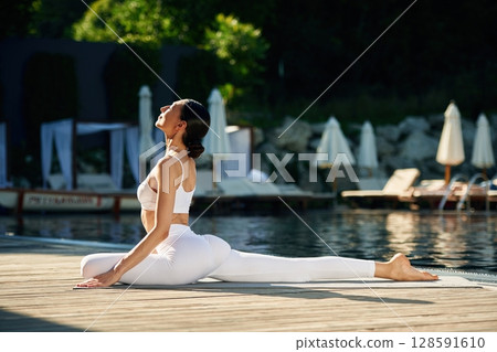 Doing yoga exercises. Woman near pool 128591610