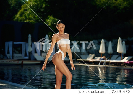 Summetime season resort. Woman in white underwear is near the pool 128591670