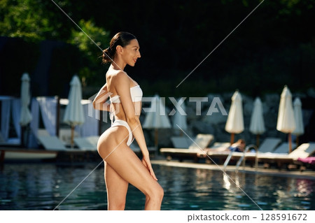 Summetime season resort. Woman in white underwear is near the pool Summetime season resort. Woman in white underwear is near the pool 128591672