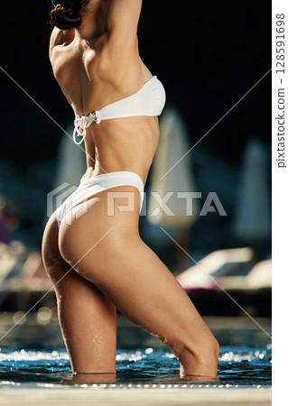Standing, showing slim body type. Woman in white underwear is in the pool Standing, showing slim body type. Woman in white underwear is in the pool 128591698