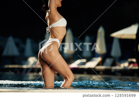 Standing, showing slim body type. Woman in white underwear is in the pool 128591699