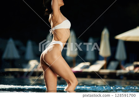 Standing, showing slim body type. Woman in white underwear is in the pool 128591700