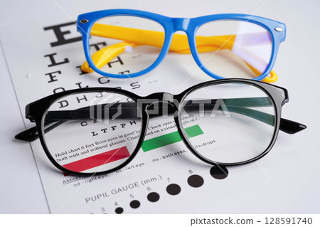 Glasses on eye exam chart to test eyesight accuracy of reading. Glasses on eye exam chart to test eyesight accuracy of reading. 128591740