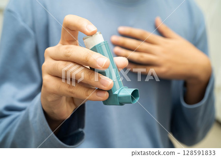 Asthma and chronic obstructive pulmonary disease COPD, Asian young man using metered dose inhaler MDI. 128591833
